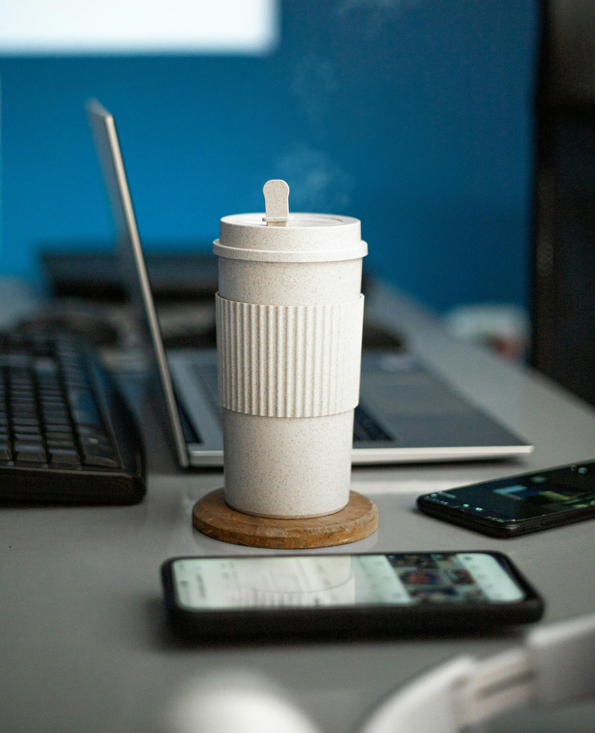 Coffee cup and laptop on office desk A coffee cup on a desk beside a laptop and smartphone, symbolizing work and digital tools
